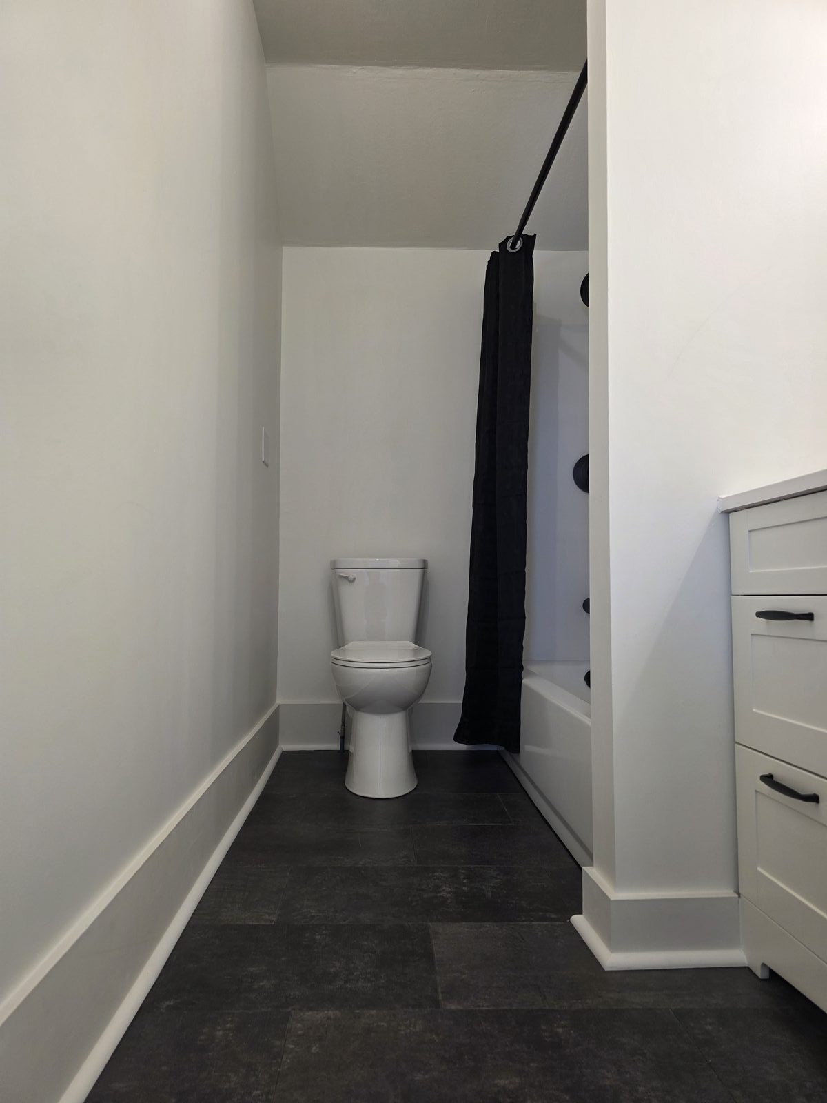 Modern bathroom remodel with dark tile and white vanity